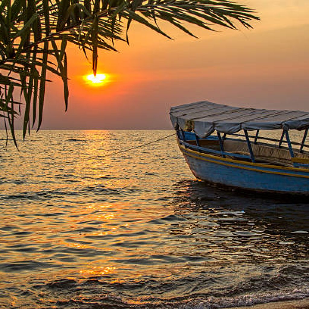 Beautiful view on moored boat on waves against of sunset at sea. Lake Victoria, Tanzania
